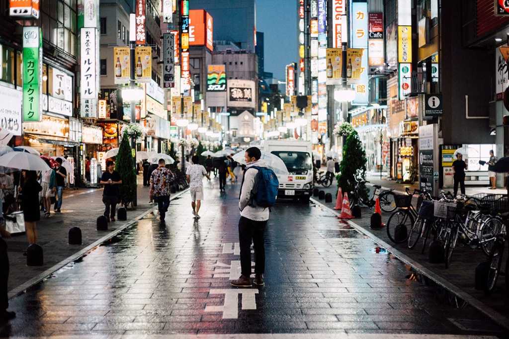 a man stands in the middle of a city street at night / Tokyo, Japan