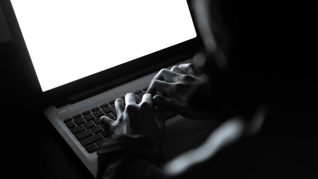 hacker doing bad things on laptop